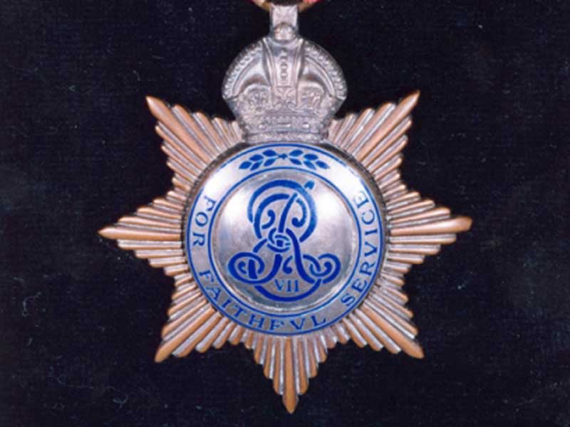 A silver and gold star-shaped medal with the cypher for Edward VII in the centre, and the words "For faithful service" printed around the edge in blue.