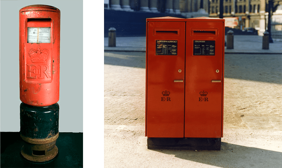 A red pillar box with the letters 'ER' is on the left. To the right, a pair of joined, rectangular metal boxes stand on the side of a street - each one has a slot for letters.