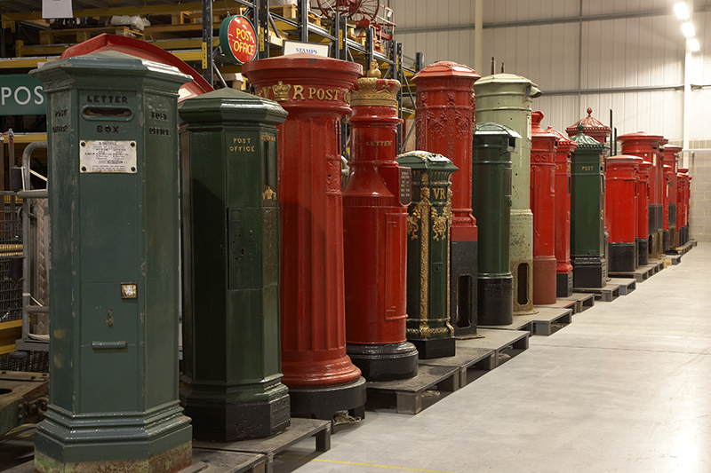 A long line of red and green post boxes in a row, in varying sizes and widths.