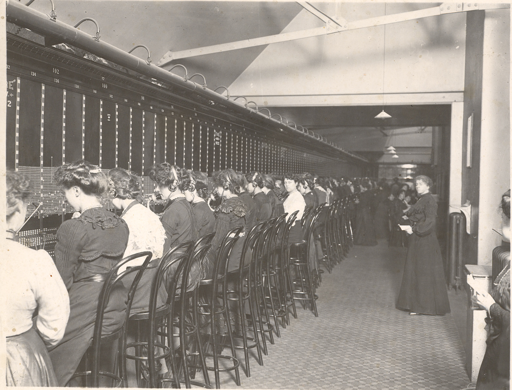 A black and white image of women working at a telephone switchboard.