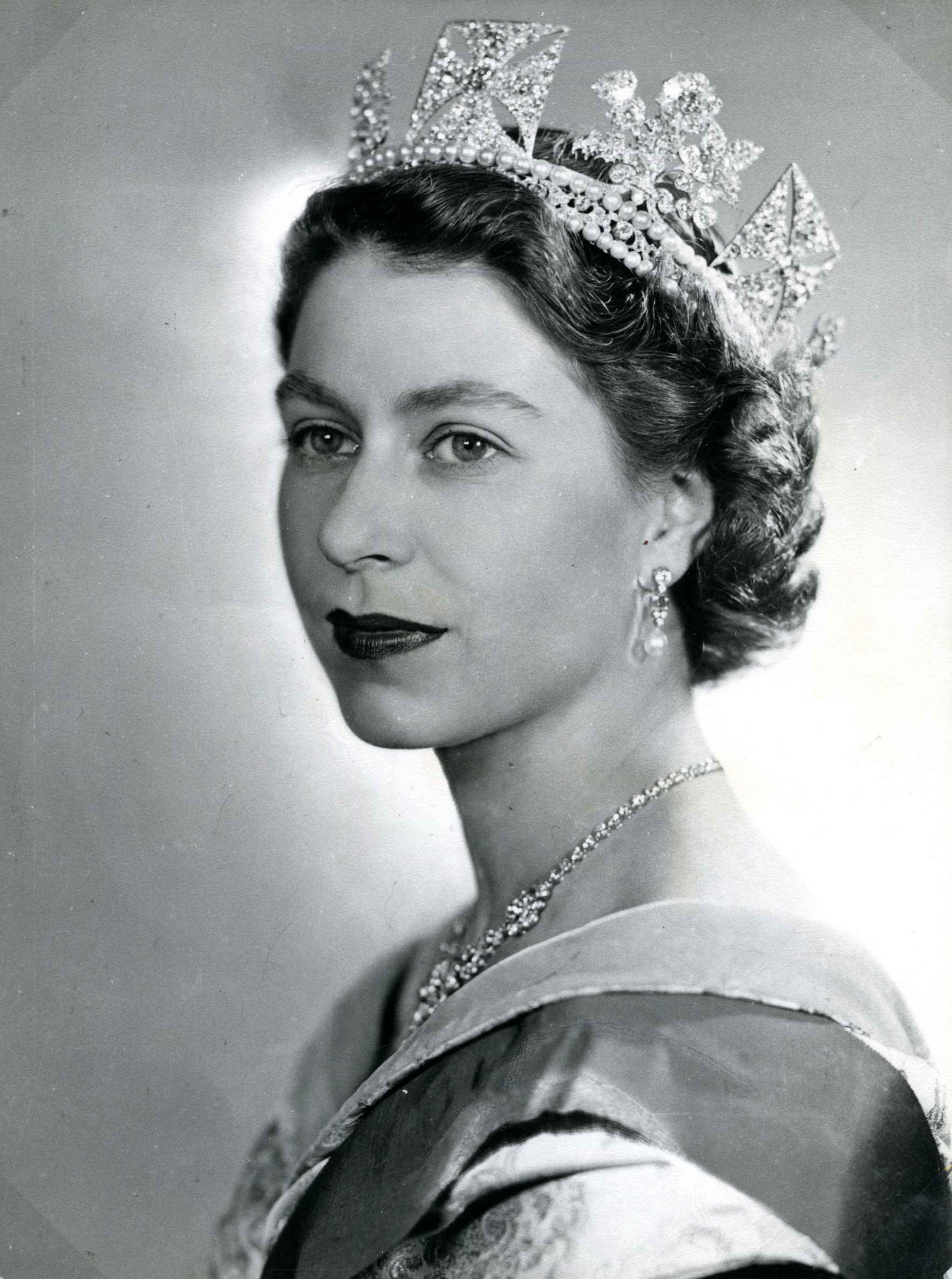 Black and white image of the Queen in three-quarter pose wearing a crown. 