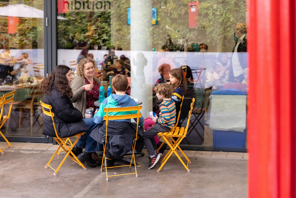 A family sitting around a small table in the outdoor cafe area.