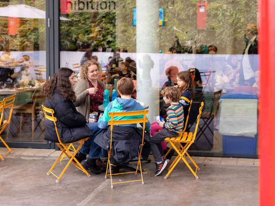 A family sitting in the outdoor cafe area at The Postal Museum.